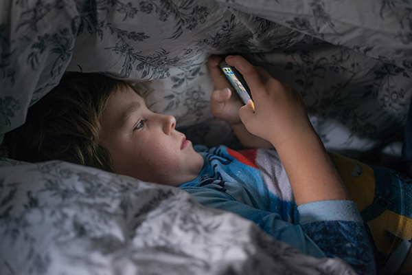 Boy using cell phone in bed